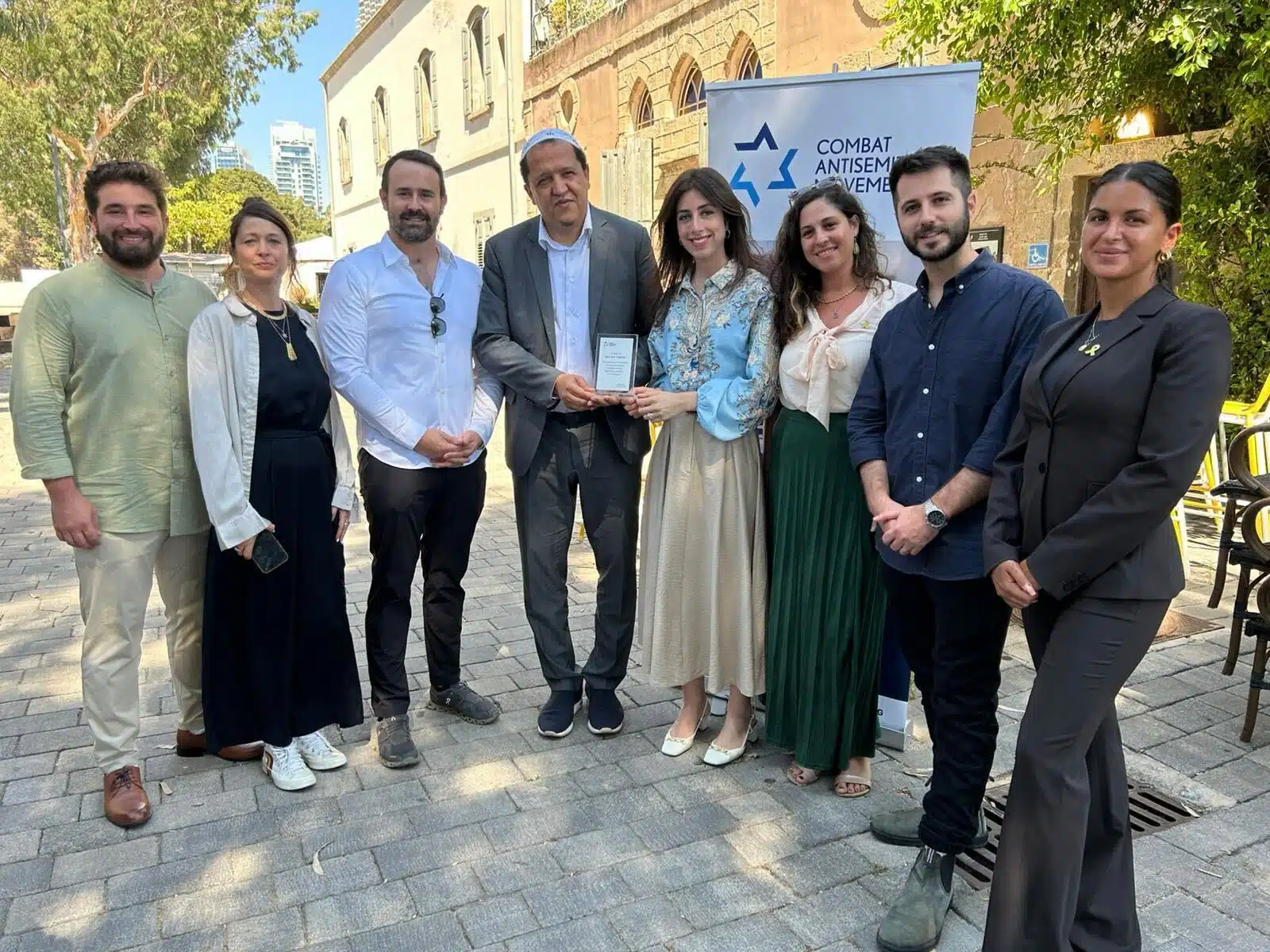 French Imam Hassen Chalghoumi (fourth from left) stands with members of the Combat Antisemitism Movement team in Tel Aviv, Israel, holding a commemorative plaque honoring his leadership in promoting peace and combating antisemitism.
