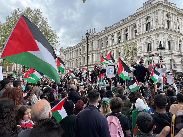 Crowd of protesters holding Palestinian flags during a pro-Palestinian demonstration outside a government building in London.