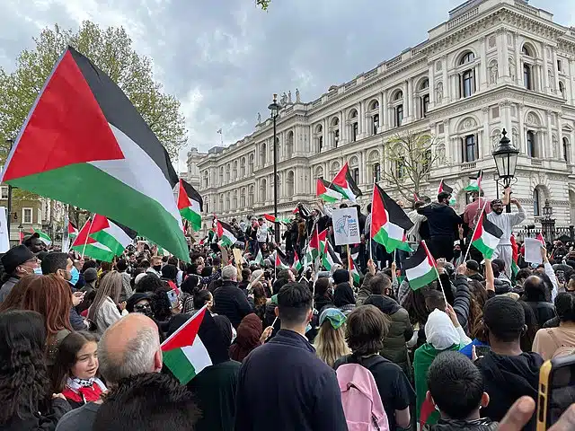 Crowd of protesters holding Palestinian flags during a pro-Palestinian demonstration outside a government building in London.