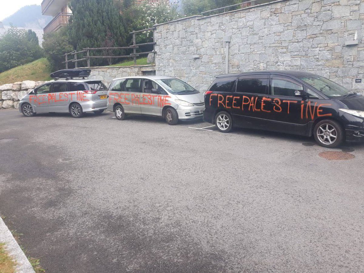Three cars parked in Chatel, France, defaced with large red spray-painted graffiti reading “Free Palestine” across their sides.