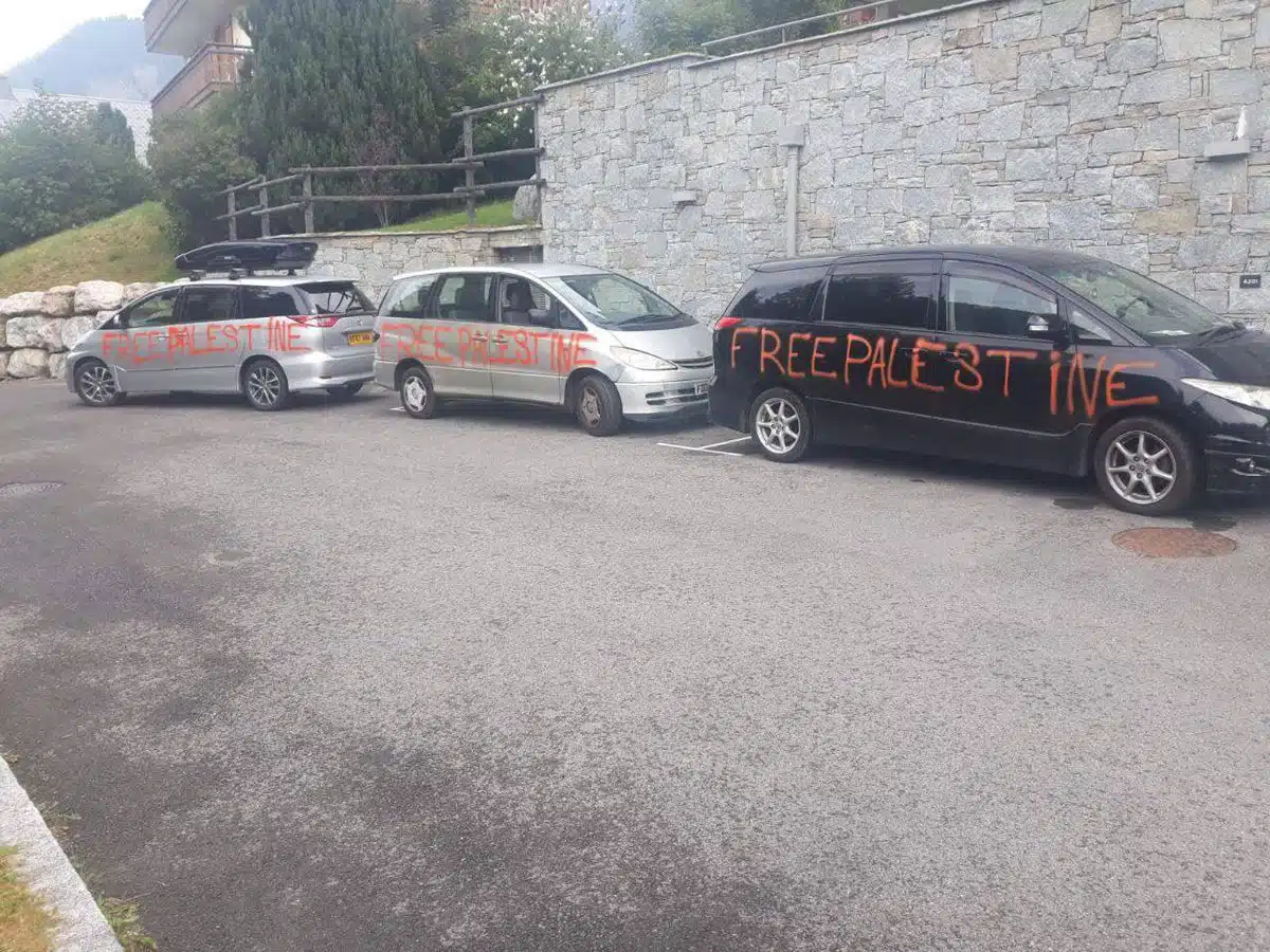 Three cars parked in Chatel, France, defaced with large red spray-painted graffiti reading “Free Palestine” across their sides.