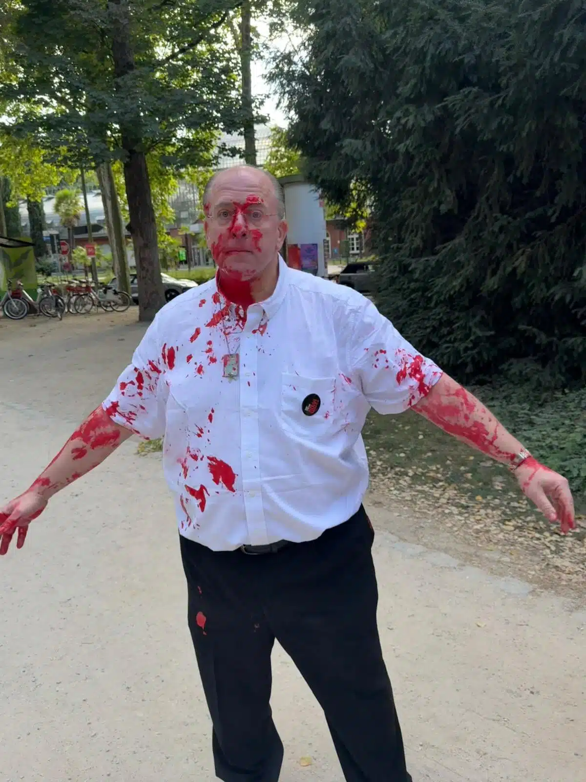 A Frankfurt Jewish activist stands covered in red paint after being attacked during a vigil for Israeli hostages in Grunburg Park.