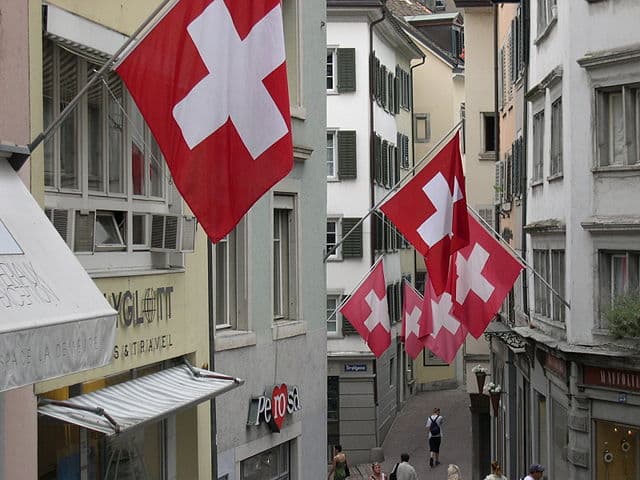 Swiss flags hanging over a narrow street in Switzerland