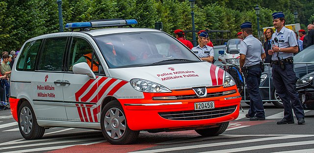 Belgian military police vehicle with officers standing nearby during a security operation in Brussels.