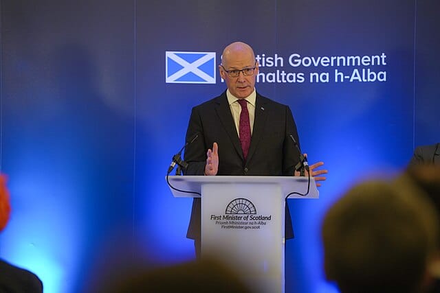 First Minister of Scotland John Swinney delivers a speech at a podium during a government event.