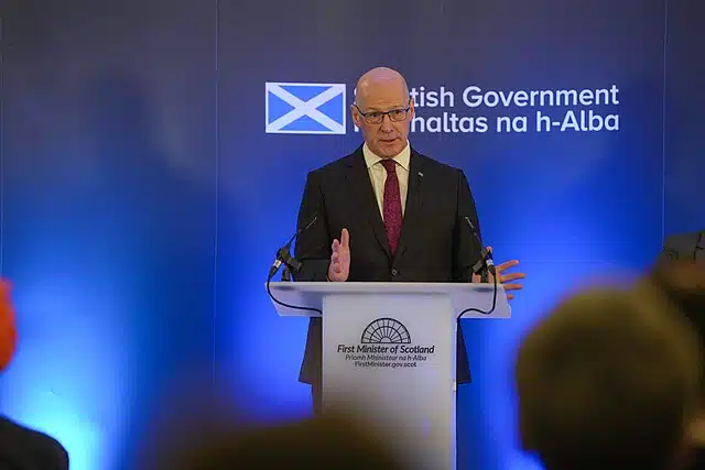 First Minister of Scotland John Swinney delivers a speech at a podium during a government event.