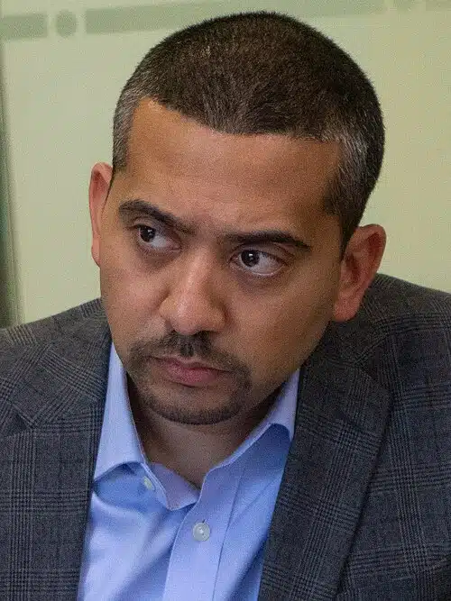 British journalist Mehdi Hasan at an event, looking serious and attentive.