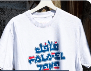 White t-shirt printed with the word “falafel” in Hebrew, English, and Arabic, symbolizing coexistence among cultures.