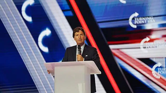 Tucker Carlson speaks at a podium onstage
