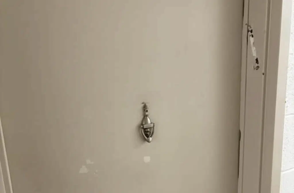 Ripped mezuzah casing removed from a doorframe at a residential building.