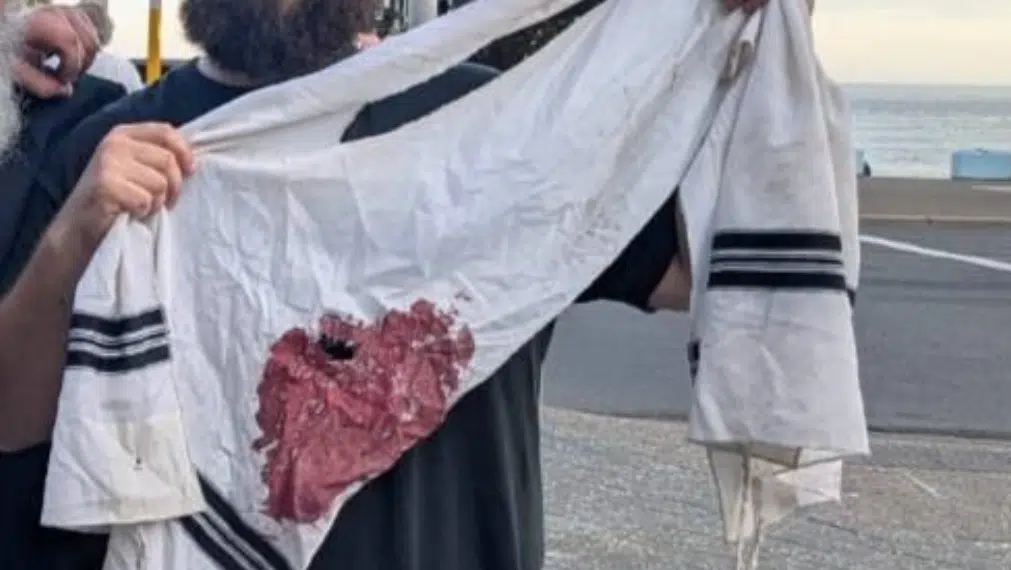 A man holds a bloodstained Jewish prayer shawl after a terror attack targeting a Hanukkah celebration at Bondi Beach in Sydney.