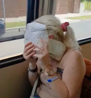 A woman seated on a Melbourne tram covers her face with a bag after an antisemitic verbal attack on a Jewish family.