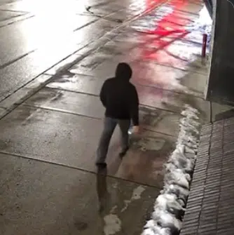 Surveillance image showing a hooded suspect walking near Michigan State University Chabad after antisemitic vandalism involving rock-throwing and swastika graffiti.