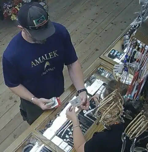 Man wearing a shirt reading “Amalek” purchases fireworks at a retail counter, as captured in surveillance footage later cited by federal investigators.