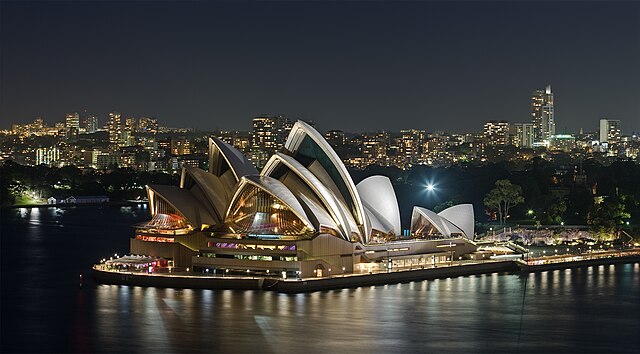Sydney Opera House illuminated at night in Sydney Harbour, the city hosting the Biennale of Sydney art festival.