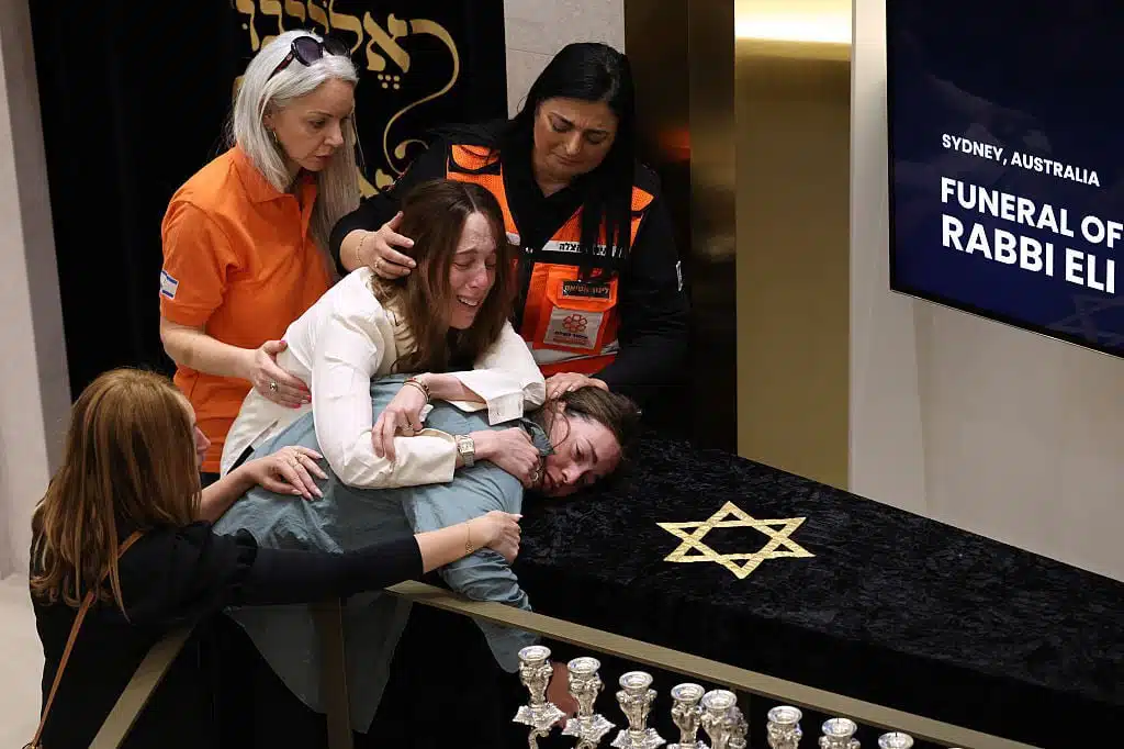 Mourners grieve over a victim at a Jewish funeral service in Sydney, Australia, following the deadly Bondi Beach massacre