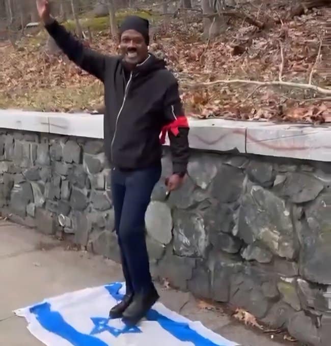 Man dressed as Hitler performs a Nazi salute while standing on an Israeli flag along the Boston Marathon route.