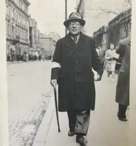 Black-and-white photograph of Linda Margolin Royal’s great-grandfather walking in the Warsaw Ghetto wearing a Jewish armband under Nazi rule.