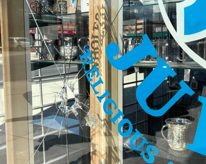 Shattered front window of a Jewish-owned Judaica store in Toronto after a violent attack, marking the third time the business has been targeted.