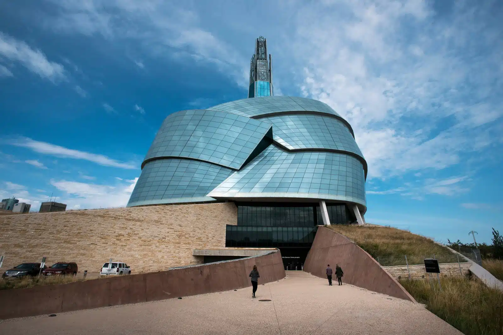 Exterior view of the Canadian Museum for Human Rights in Winnipeg, Manitoba, featuring the museum's distinctive curved glass architecture under a blue sky.