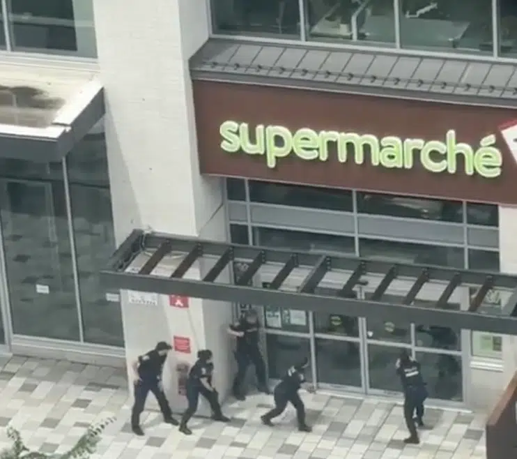 Police officers move toward the entrance of a supermarket during an active security operation in Montreal's Côte-des-Neiges neighborhood.