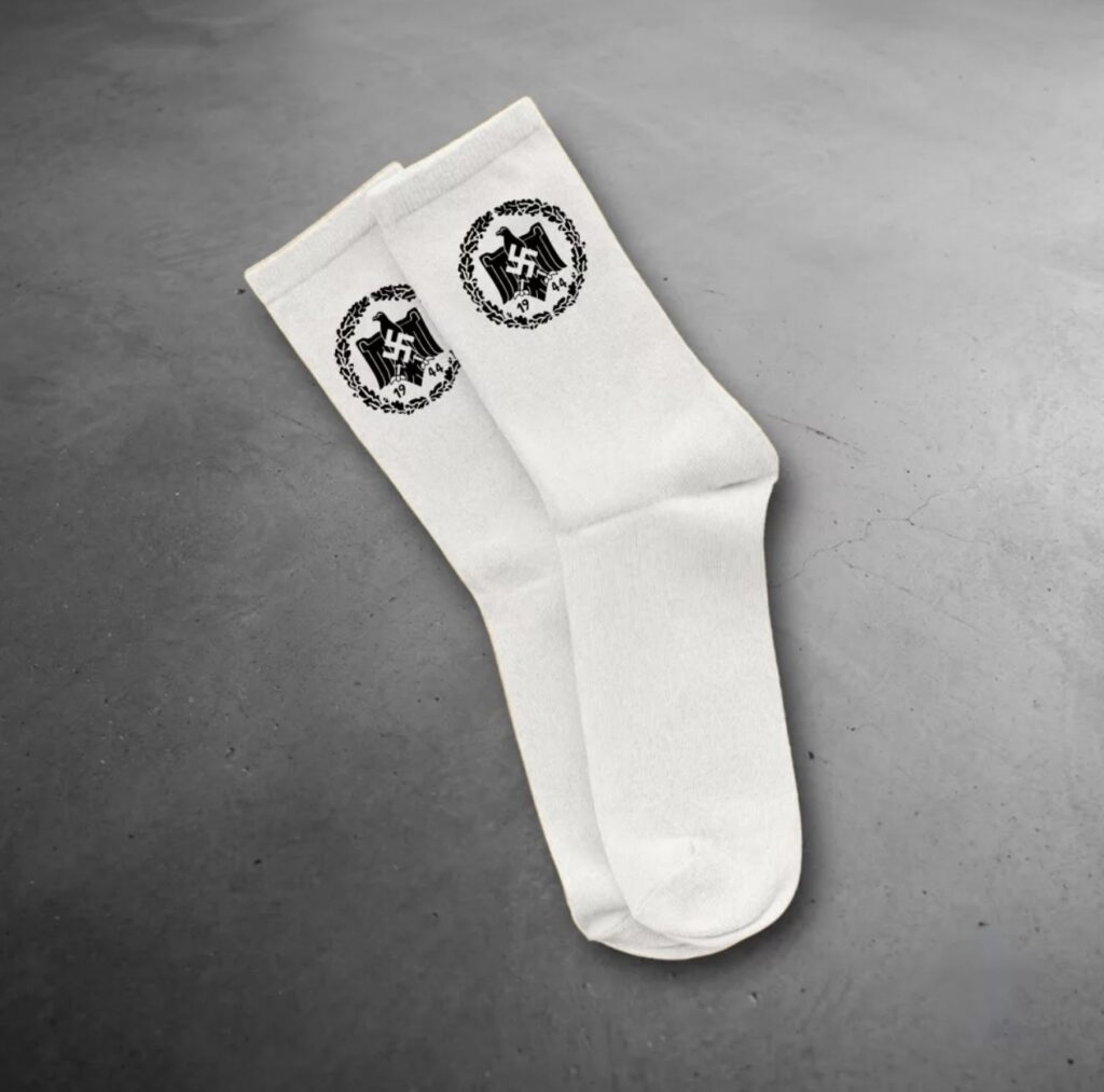 White socks displayed with a black Nazi-era eagle-and-swastika emblem marked "1944," part of an Instagram product listing that was recommended to a CAM account before Meta removed it.