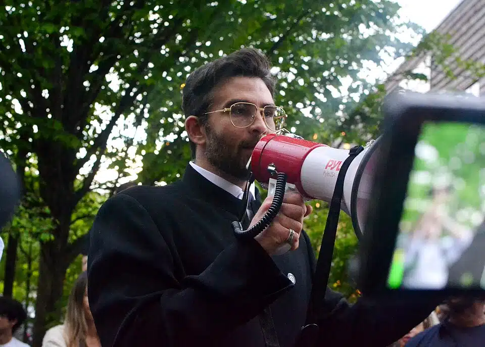 Hasan Piker speaks into a megaphone at an outdoor gathering