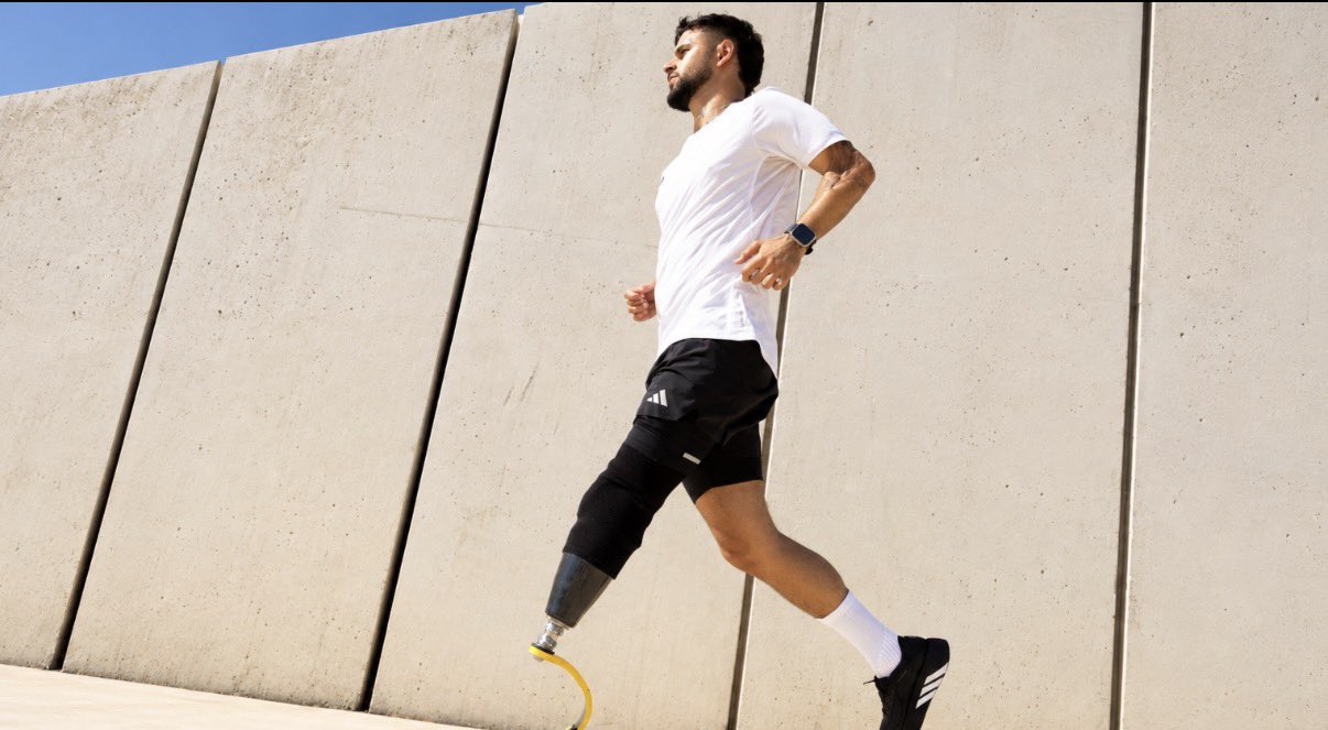 Shalev Biton runs outdoors on a prosthetic left leg while wearing Adidas athletic shoes.
