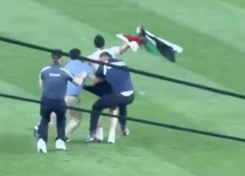 Security officers restrain a man carrying a Palestinian flag on the field at Yankee Stadium.