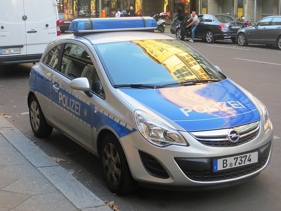 A silver and blue German police car marked "Polizei" parked on a street in Berlin.