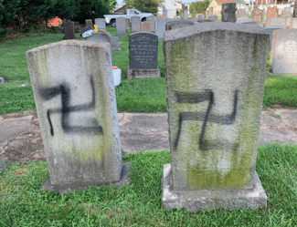 Two gravestones defaced with black spray-painted swastikas at a Jewish cemetery outside Baltimore, Maryland.