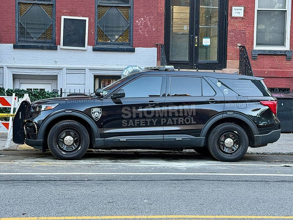 Black Manhattan Shomrim Safety Patrol SUV parked along a New York City street outside a brick building.