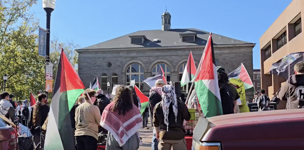 Demonstrators carrying Palestinian flags gather outside a stone building at Seattle Central College.